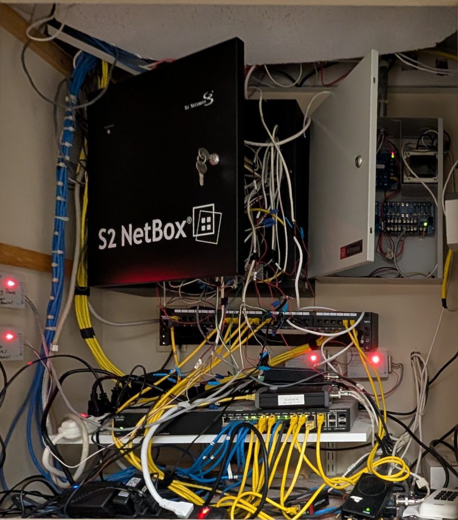 S2 NetBox access control panel with tangled wiring and network connections, illustrating complexities of modern security system installations.