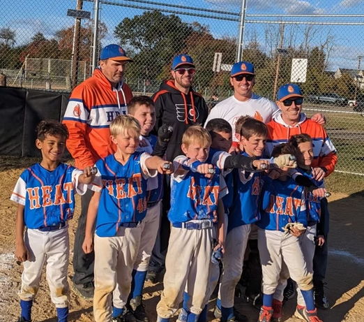 Youth baseball team "HEAT" posing with coaches, showcasing teamwork and community spirit in a local sports event.